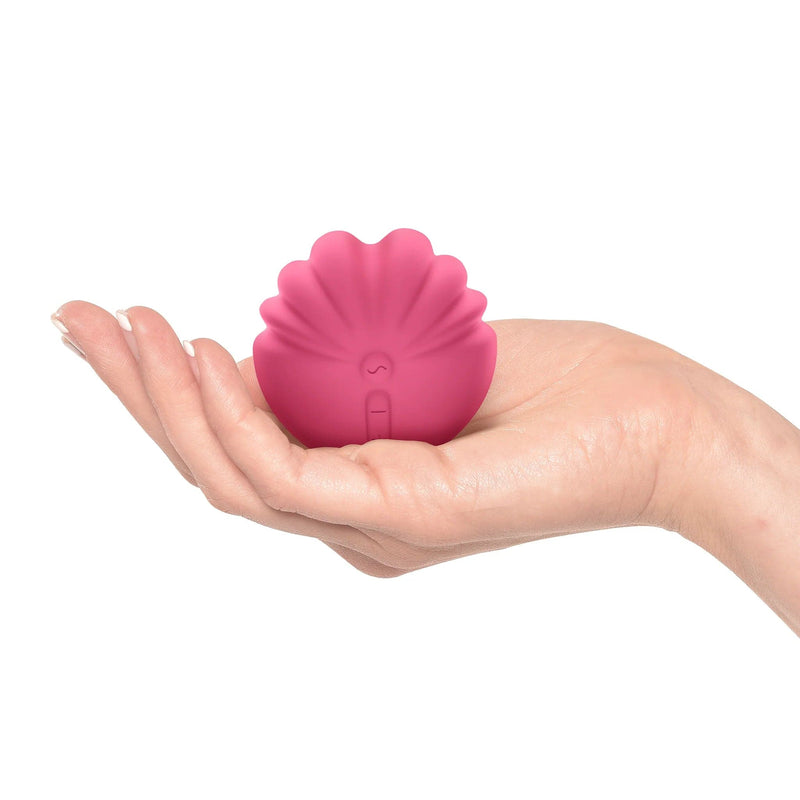 Front-facing shell shape clitoral vibrator pink in the palm of a white woman&