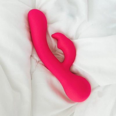 Silicone rabbit vibrator pink on top of a bed