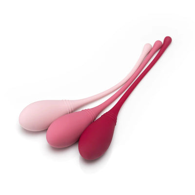 Self + Jimmyjane small, medium, and large kegel trainers set in light pink, pink, and burgundy laying on table
